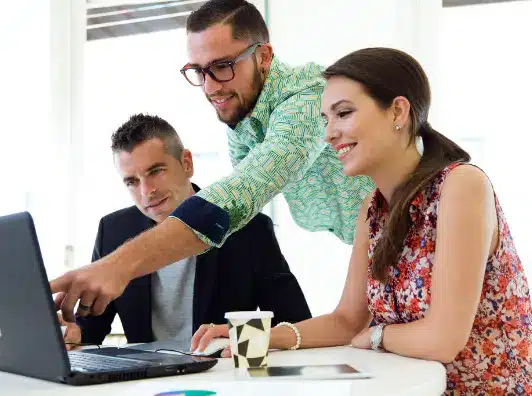 Three USA Payments team members collaborating on merchant account solutions at a laptop