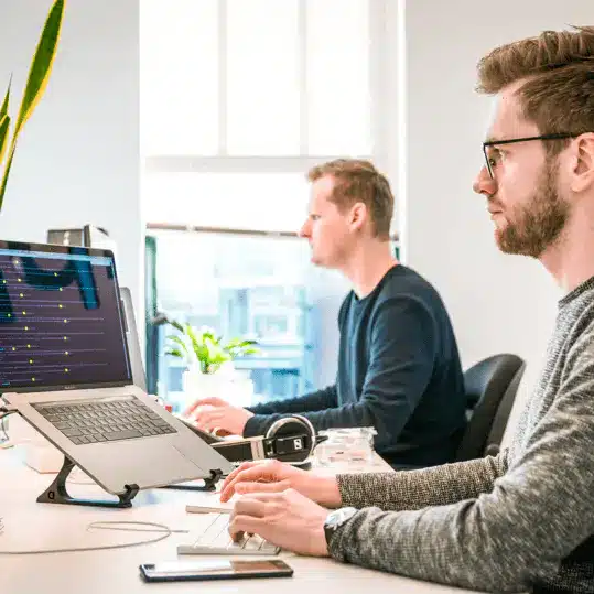 Two payment processing specialists working at computers in a modern office