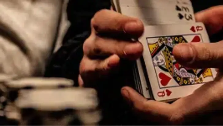 Player holding a hand of playing cards at a gaming table