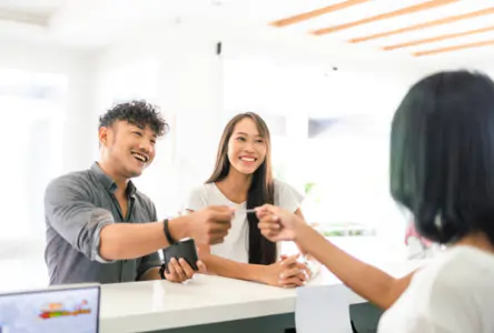 Client handing a credit card to the front desk to pay for a treatment at a wellness clinic checkout