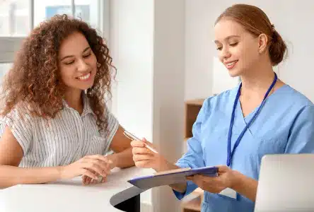 Wellness clinic staff member reviewing a client’s membership plan on a tablet at the front desk